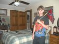 Dylann in his bedroom holding a small Confederate flag